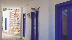 A corridor with blue doors and a stone wall. - Occasus Comfort Room (Halki)