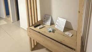 A room with a wooden bed frame, a mounted TV, and a small table with a remote control and informational cards. - Occasus Comfort Room (Halki)