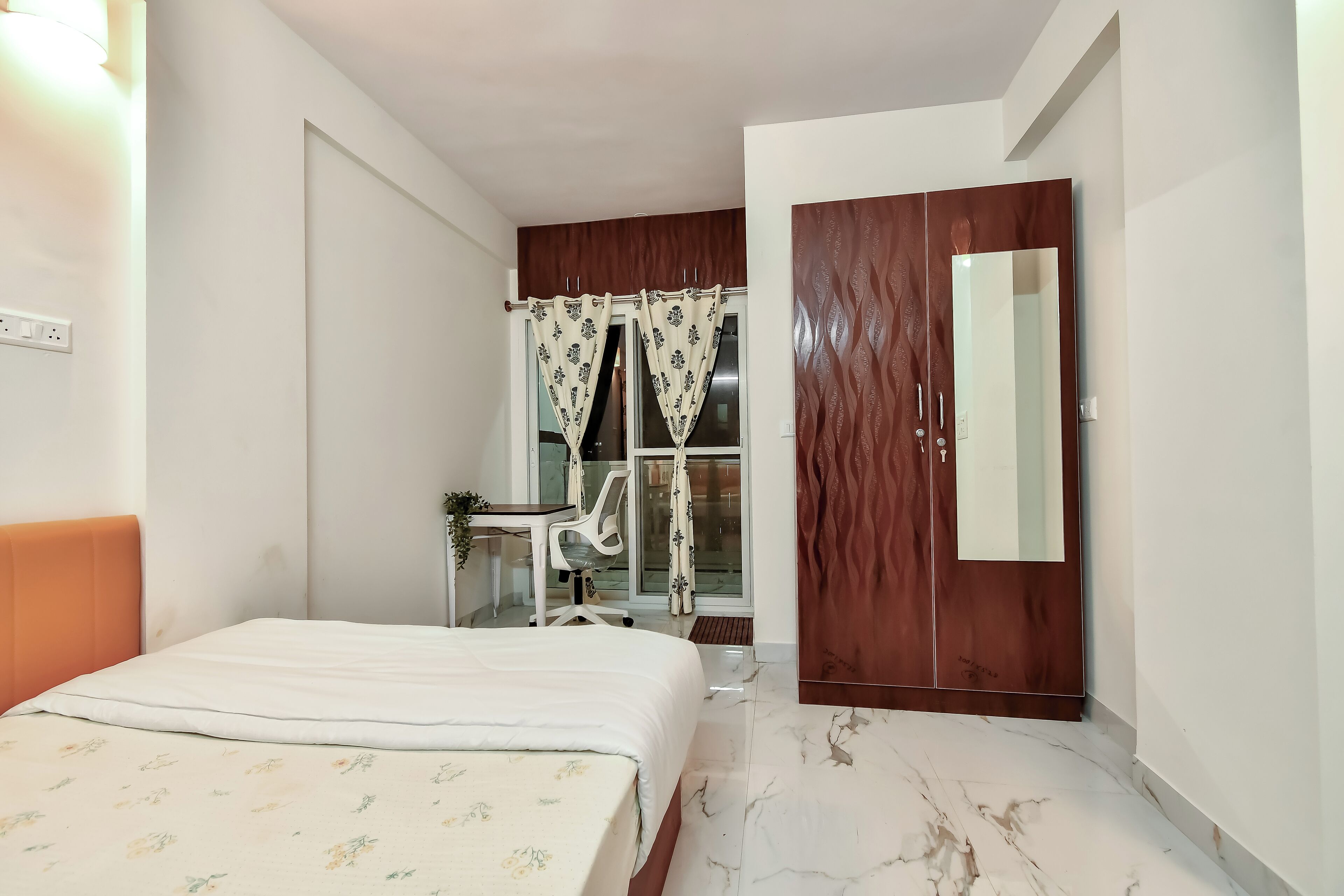 Un dormitorio con cama, armario de madera, escritorio con silla y ventana con cortinas.