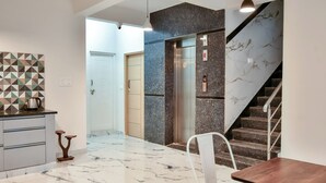 A modern kitchen with marble flooring, a wooden dining table, and a white chair. - Namma HomeSlice (Bengaluru)