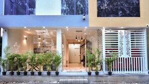 A modern building with a glass storefront, potted plants, and a white gate with decorative elements. - Namma HomeSlice (Bengaluru)