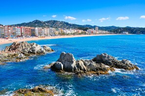 A coastal cityscape with a beach, rocky outcrops, and a row of buildings along the shore. - Santa Cristina 6 in Lloret de Mar (Lloret de Mar)