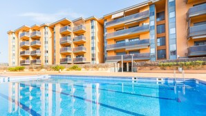 Ένα σύγχρονο ξενοδοχείο με πολλά μπαλκόνια, μια πισίνα και έναν καθαρό ουρανό.