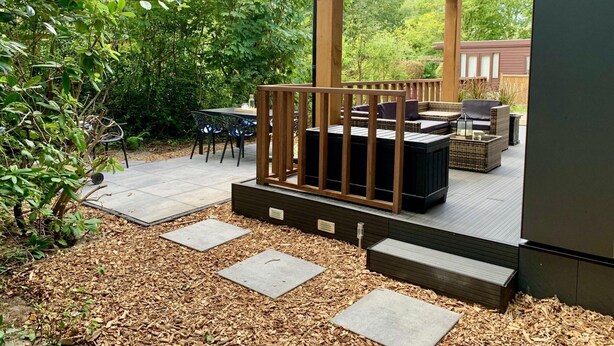 Une terrasse extérieure couverte, dotée d’une plateforme en bois, d’un espace salon et d’une table avec des chaises.