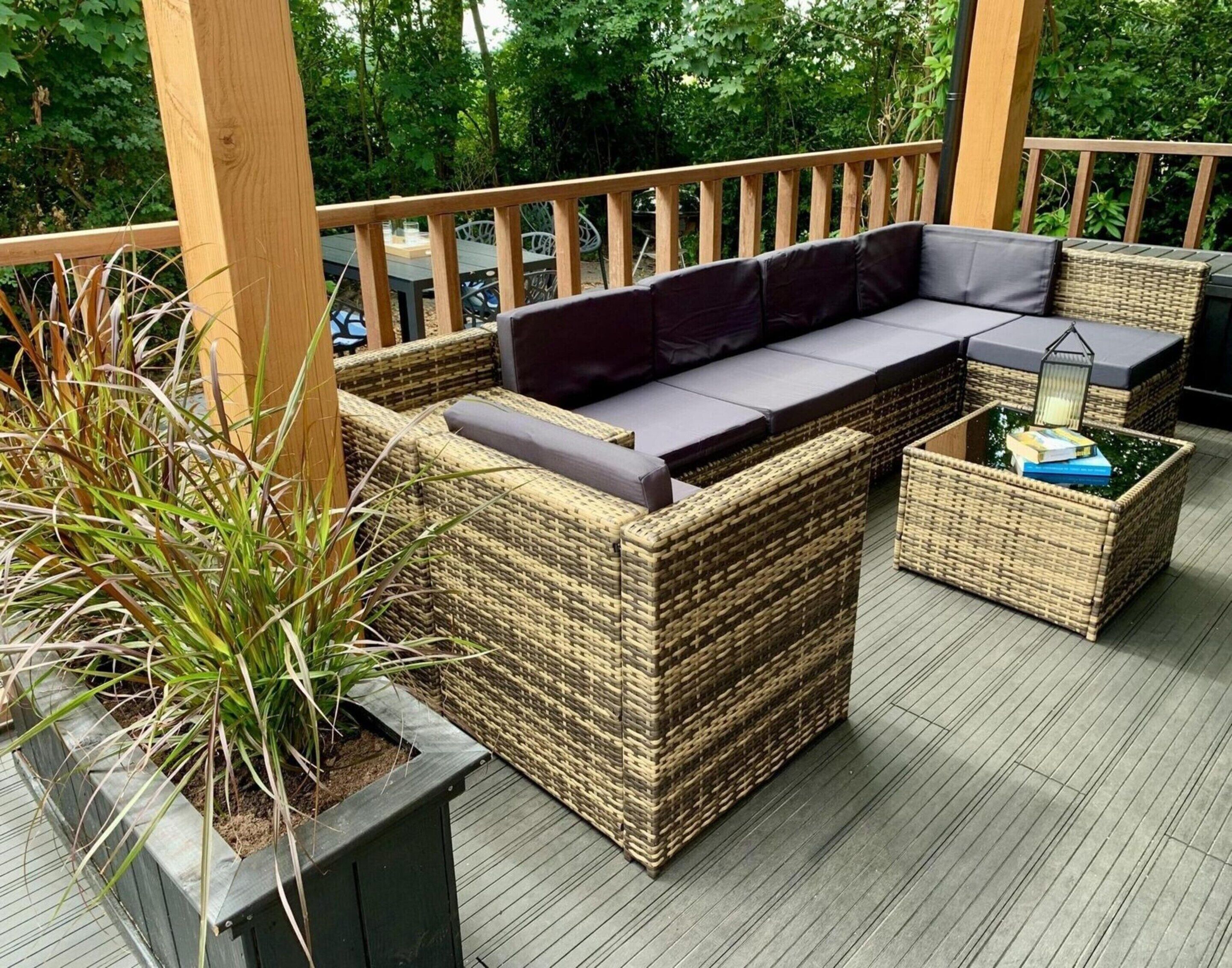 A covered outdoor seating area with wicker furniture and a cushioned bench.
