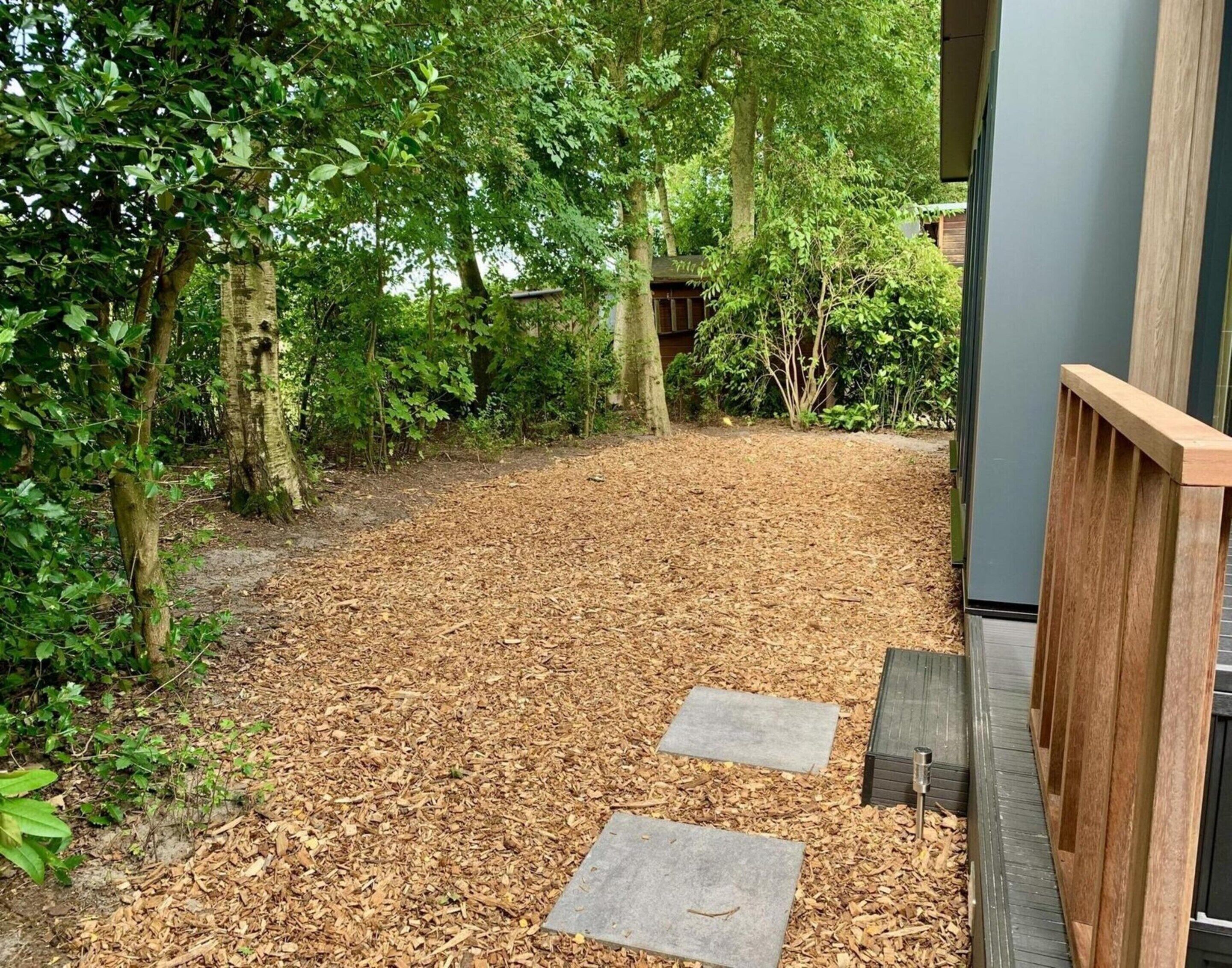 A pathway leading to a building with a wooden fence and a metal gate.