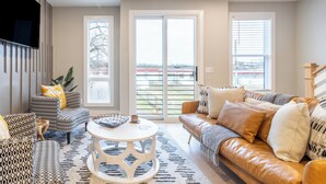 A living room with a patterned sofa, a leather couch, and a round coffee table. - Monty by AvantStay | 4BDR 4BA | Balcony + Outdoor Seating | Minutes to Downtown (Nashville)