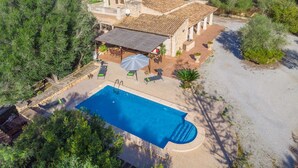 En villa med swimmingpool, udendørs siddepladser og en stenbelagt terrasse.