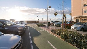 Ein Parkplatz mit Autos und einer grünen Fahrbahn für Radfahrer, ein Gebäude mit einem Schild und ein klarer Himmel.