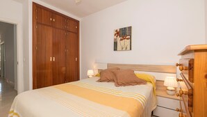 Ein Schlafzimmer mit einem großen Bett, einem Holzschrank, einem Nachttisch mit Lampen und einem Bild an der Wand.