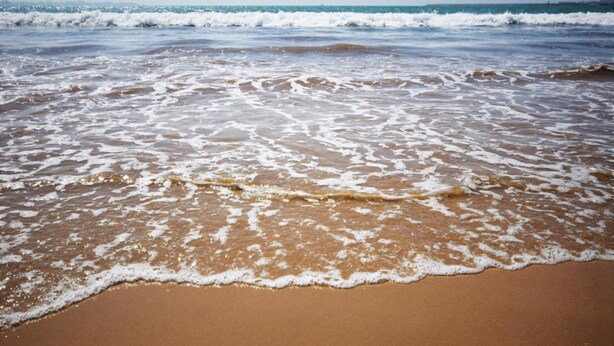 Ein Strand mit sanft anschwellenden Wellen.