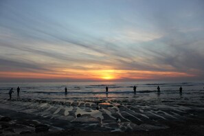 Escena de playa con gente pescando al atardecer.