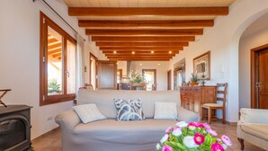 A spacious living room with a sofa, a wooden ceiling, and a view into the kitchen. - Son Morro Ca Na Poveta (Santa Margalida)