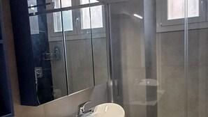 Ein modernes Badezimmer mit großem Spiegel, Waschbecken und Duschkabine.