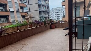 Eine Dachterrasse mit Holzboden, Pflanzkübeln und einem Metallgitter.