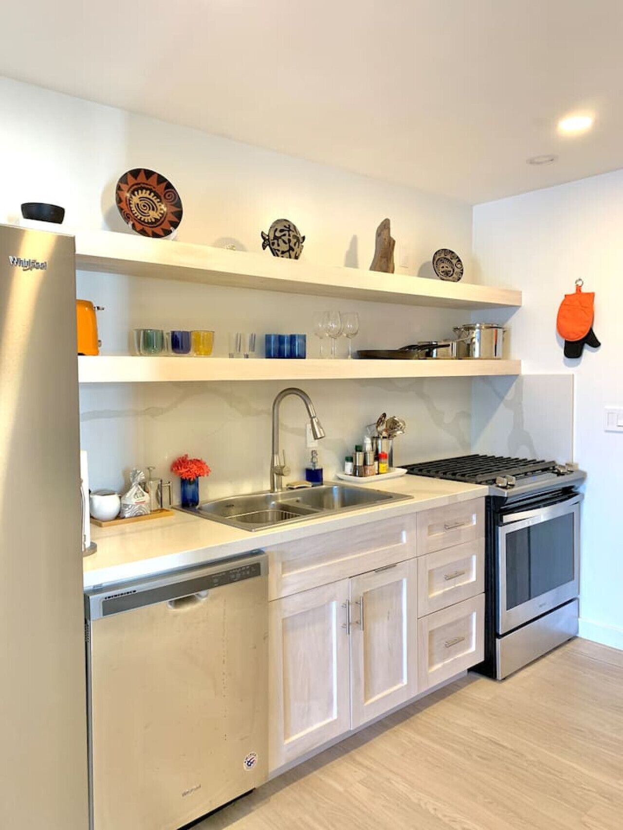 A modern kitchen with a stainless steel refrigerator, double sink, and built-in oven.