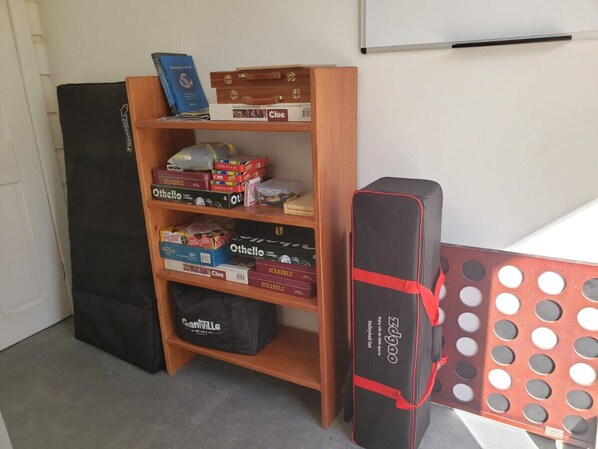 A room with a wooden bookshelf containing board games, a black bag, and a red mat with holes. - Curacion Beach Resort (Brick Bay)