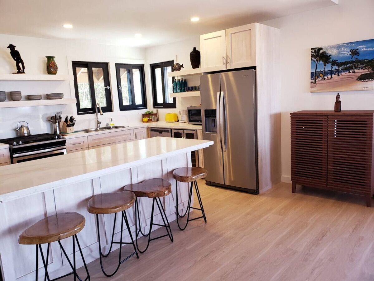 Una cocina moderna con una isla central, electrodomésticos de acero inoxidable y taburetes de madera.