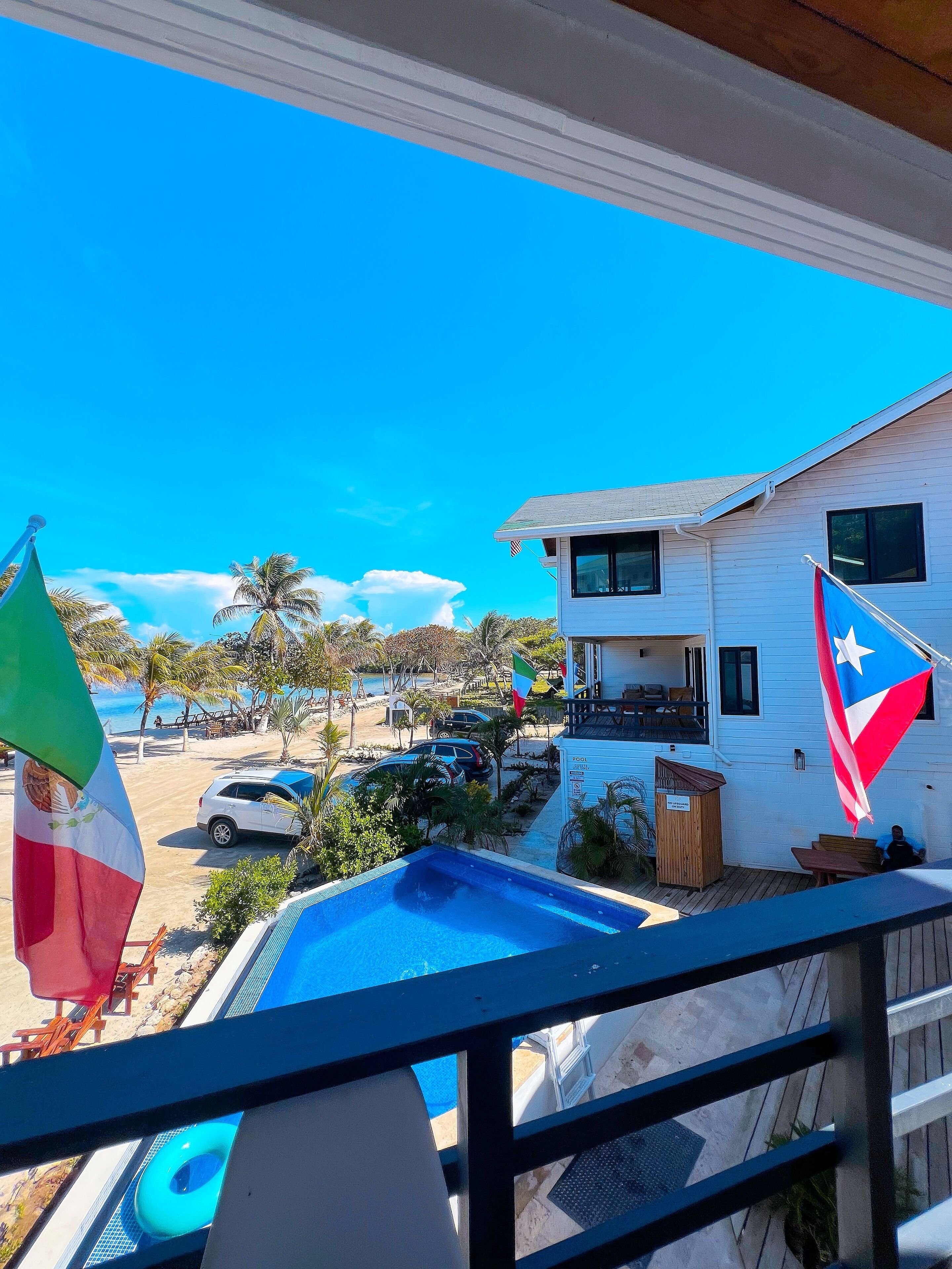 Una casa con piscina, banderas y vistas a la playa.