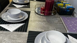 A dining table set with white plates, bowls, and a red candle. - Stunning 4bedrooms Flat (Manchester)