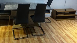 A conference room with a long table, black chairs, a clock, a framed picture, and a TV on the wall. - Stunning 4bedrooms Flat (Manchester)