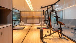 Une salle de sport moderne équipée de matériel d’exercice, dotée de planchers en bois et de murs en verre.