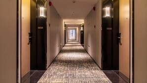 Un long couloir étroit, avec des portes de chaque côté, menant à des pièces individuelles.