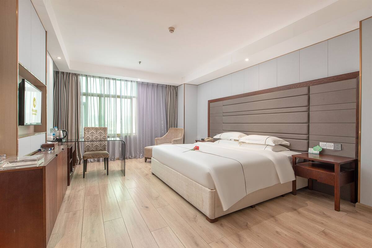 Una habitación de hotel con una cama grande, un escritorio, una silla y un televisor.