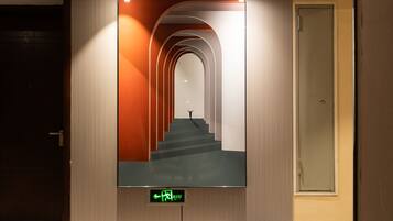 A hallway with a digital display indicating an exit and a staircase leading to another floor.