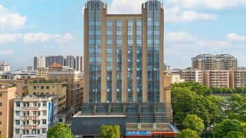 A modern high-rise building with multiple floors, surrounded by other buildings and greenery.