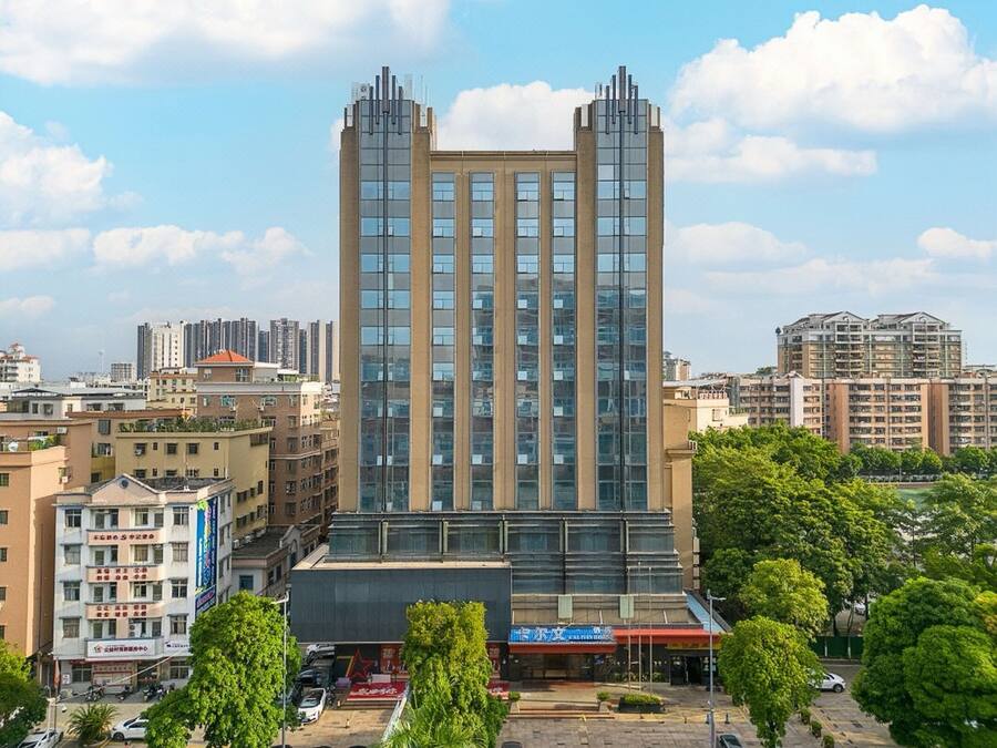 Un edificio moderno de gran altura con varios pisos, rodeado de otros edificios y vegetación.