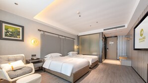 Une chambre d’hôtel moderne avec un grand lit, un canapé, une petite table et un tableau au mur.
