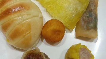 A plate with various food items including a steamed bun, a piece of yellow fruit, a fried item, a dumpling, and a boiled egg.