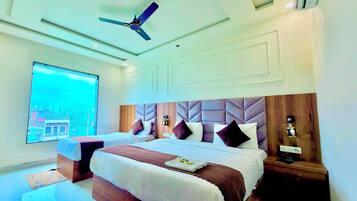 A hotel room with a large bed, a ceiling fan, a nightstand, and a view of a building outside.