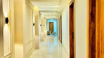 A hotel corridor with a polished marble floor, wooden doors, and recessed lighting.