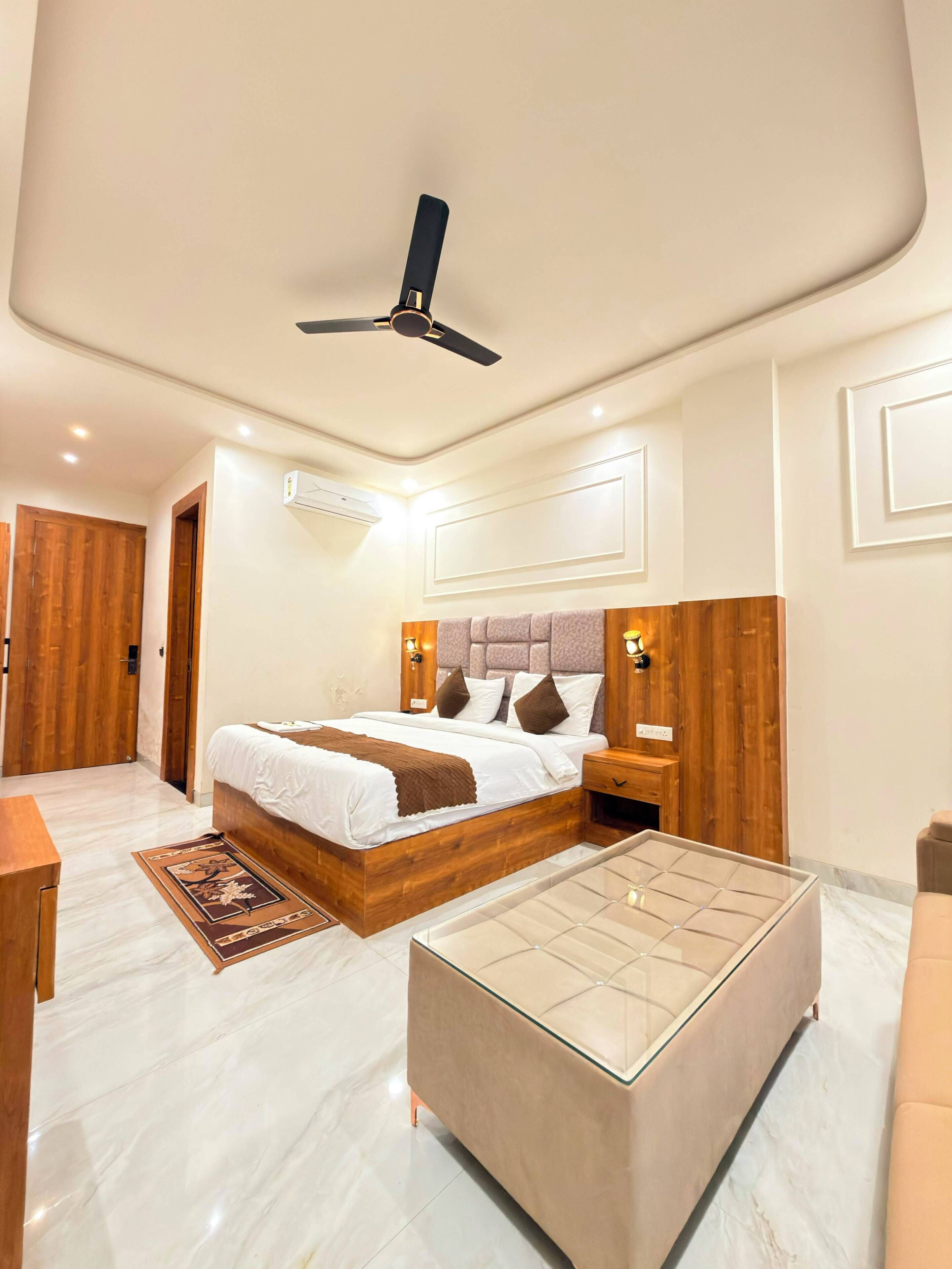 Un dormitorio con una cama, mesitas de noche, un ventilador de techo y piso de mármol.