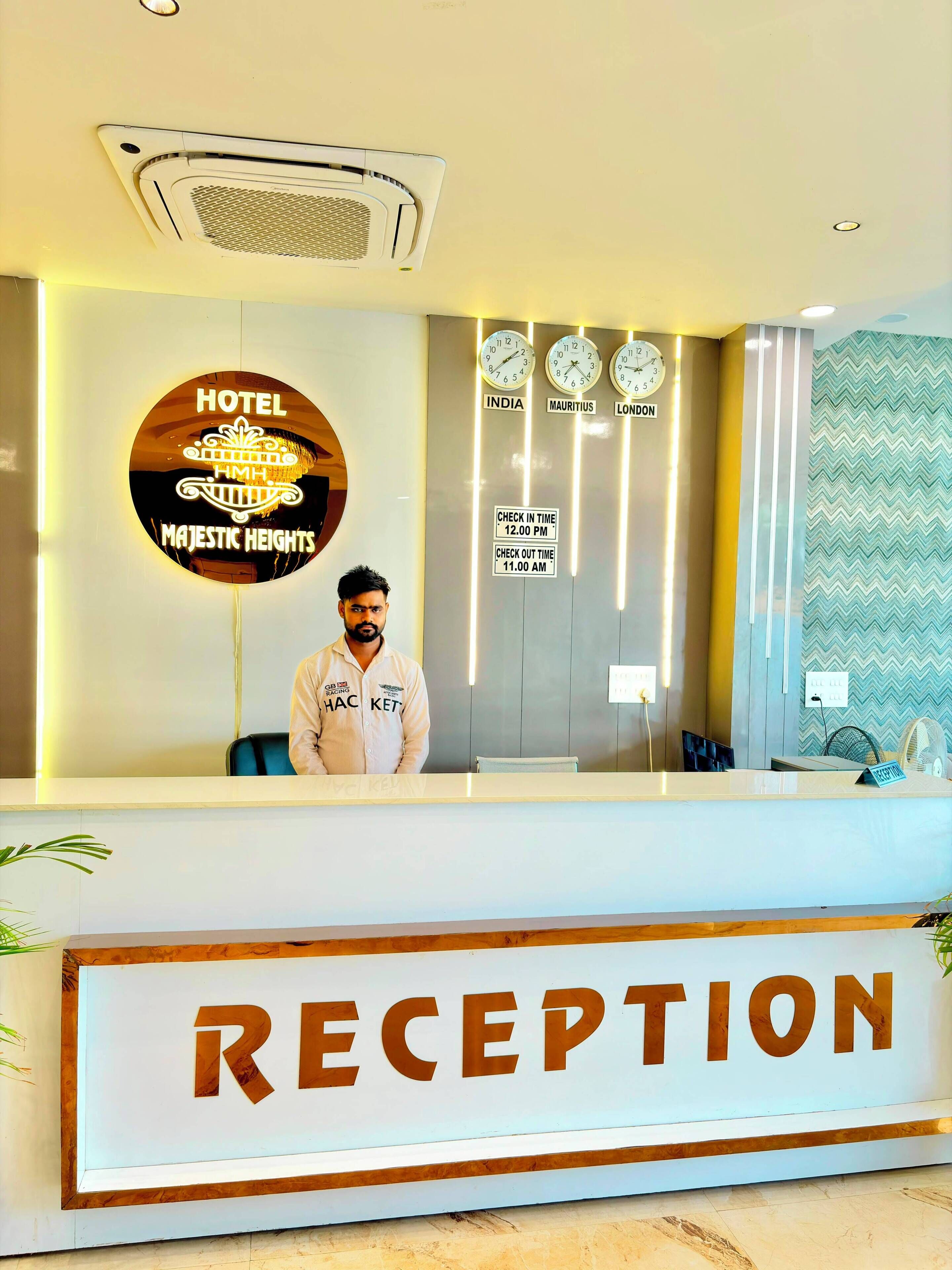 Un mostrador de recepción de hotel con un cartel que dice 'RECEPTION' y un cartel circular encima que indica 'HOTEL MAJESTIC HEIGHTS'.