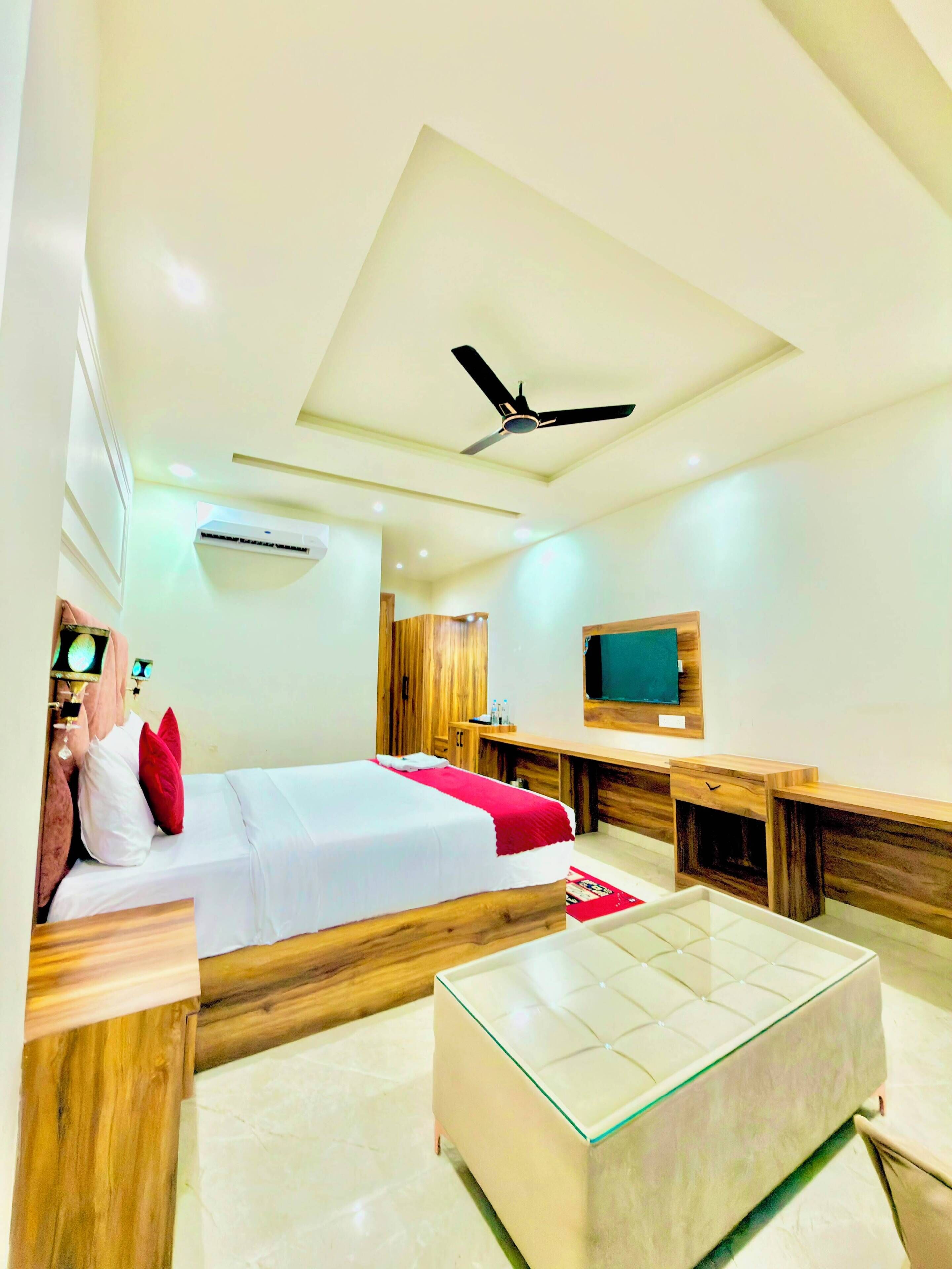 A modern hotel room with a bed, a desk, a television, and a ceiling fan.
