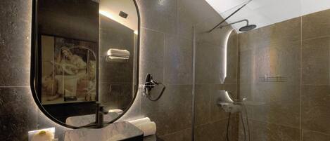 Un baño moderno con un espejo grande, ducha y tocador con artículos de aseo.