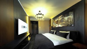 Une chambre d’hôtel avec un grand lit, un téléviseur à écran plat, un lustre et un tableau au mur.