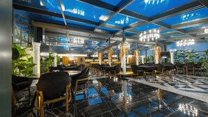 Un restaurant moderne doté d’un plafond en verre, d’un sol en marbre et de carreaux aux motifs noir et blanc.