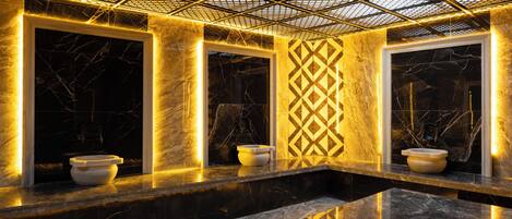 A modern bathroom with marble countertops, a geometric patterned wall, and a ceiling with a grid design.