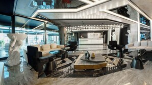 Un hall d’entrée spacieux avec un comptoir d’accueil, des sièges modernes et une grande sculpture décorative.