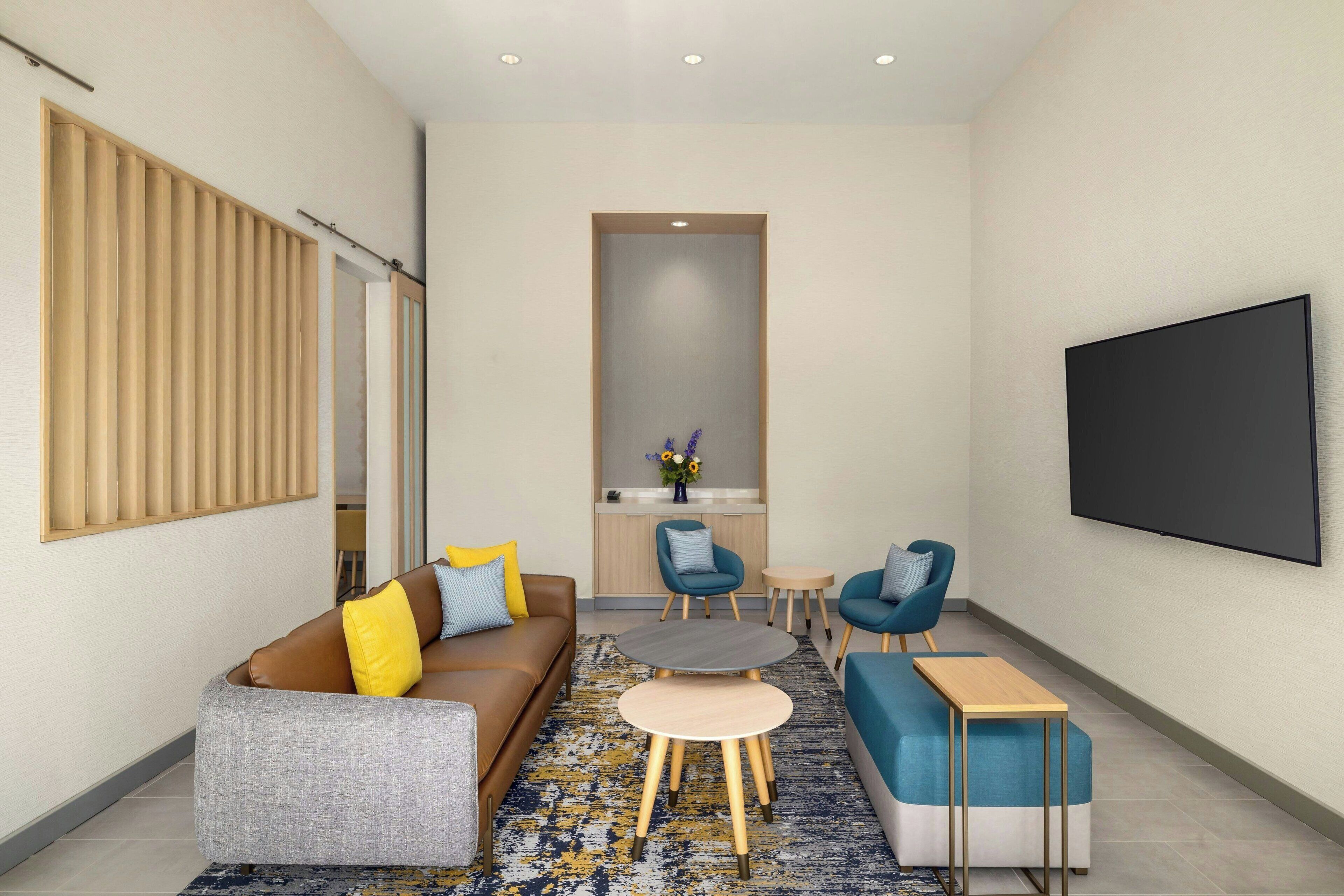 A modern living room with a sofa, two armchairs, a coffee table, and a flat-screen TV mounted on the wall.