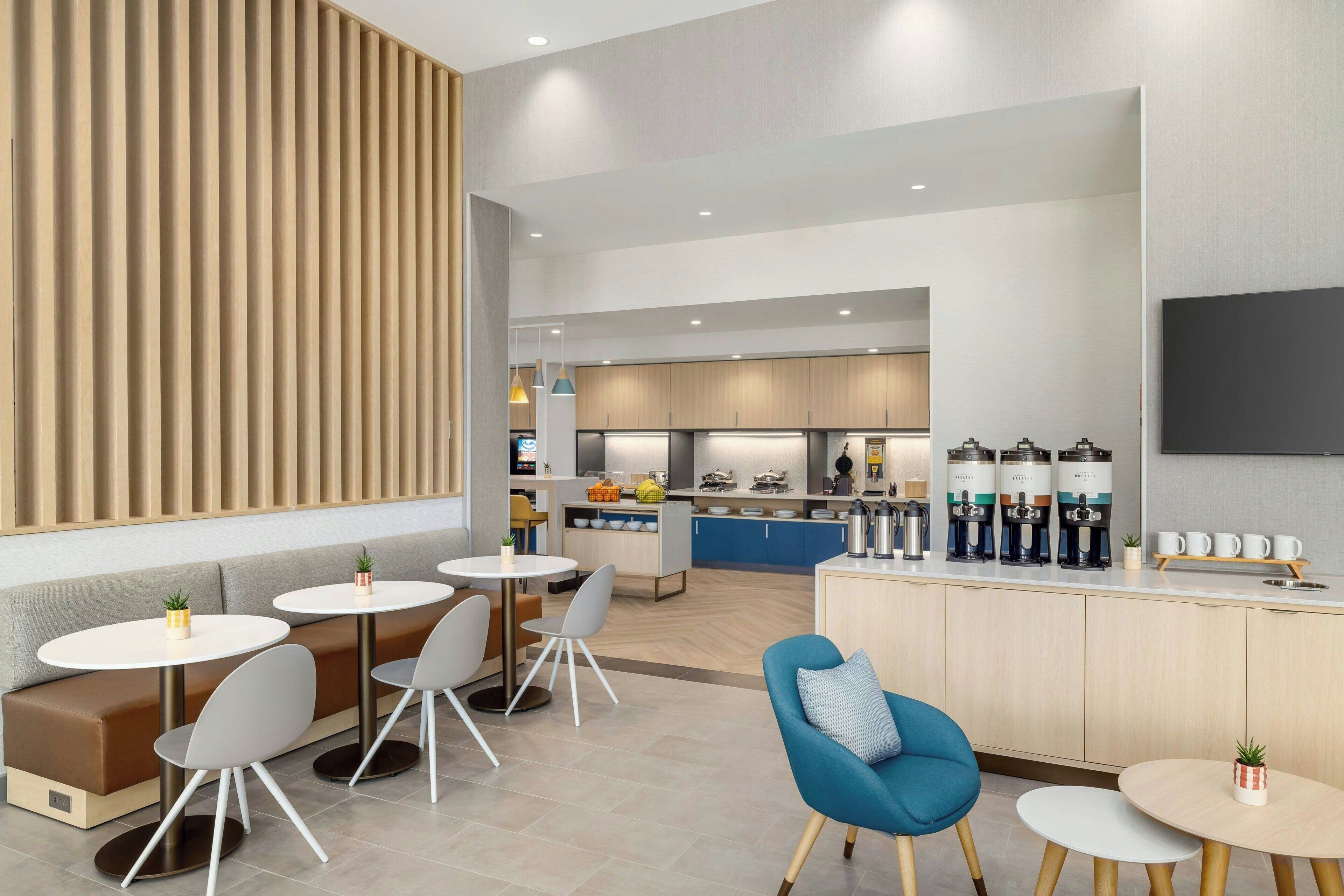 Une cuisine moderne dotée d’un îlot central, d’appareils électroménagers intégrés et d’un coin repas avec des tables et des chaises rondes.