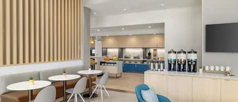 Una cocina moderna con una isla central, electrodomésticos integrados y una zona de estar con mesas y sillas redondas.