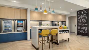 A modern kitchen with a central island, bar stools, and a refrigerator.