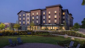 A multi-story hotel with a modern design, featuring a landscaped outdoor area with seating and a well-maintained lawn. - TownePlace Suites by Marriott Williston (Williston)