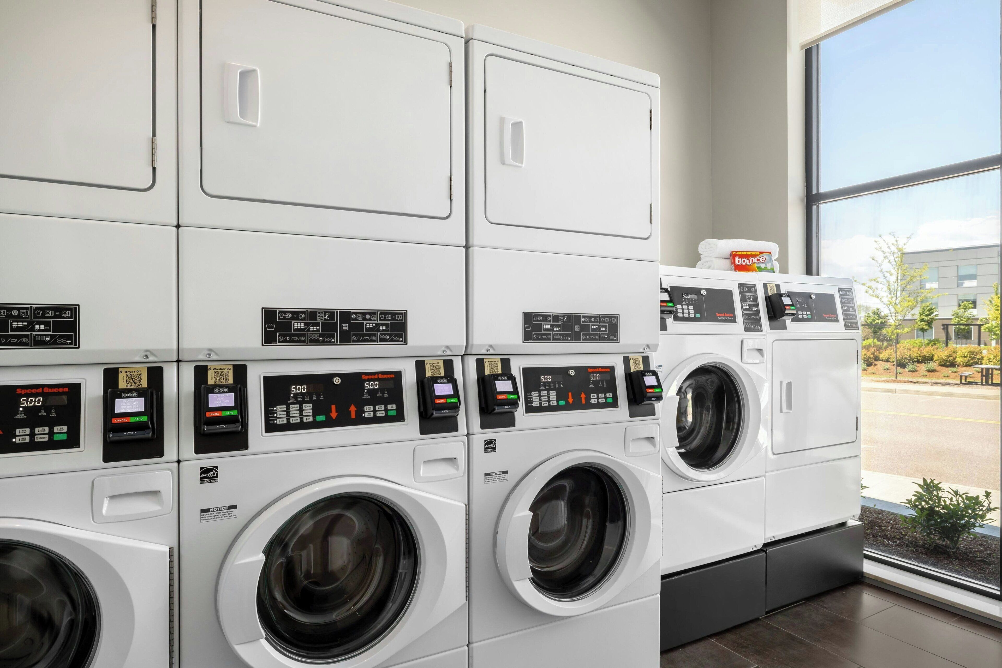 A row of white, modern, front-loading washing machines in a commercial setting.