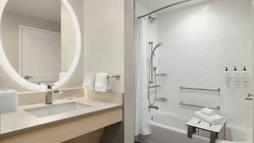 Un baño moderno con un espejo grande, dos lavamanos, una bañera y una ducha.
